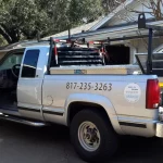 Silver Truck with Phone number on the side. Holding supplies and tools to repair a garage door.