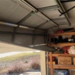 broken garage door panels. Shelves full of household objects being stored in garage.