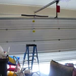 garage door spring replacement, garage full of trash, a ladder and other objects