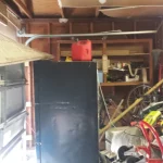 A garage full of objects with broken garage door.